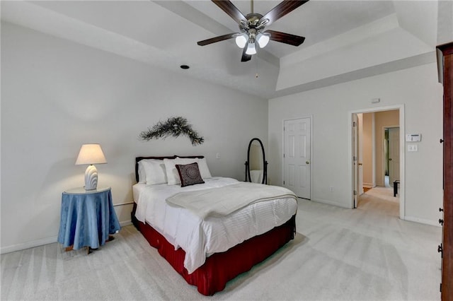 bedroom with baseboards, ceiling fan, a tray ceiling, and light colored carpet