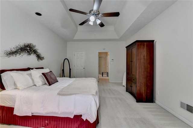 bedroom featuring visible vents, baseboards, light colored carpet, and a raised ceiling