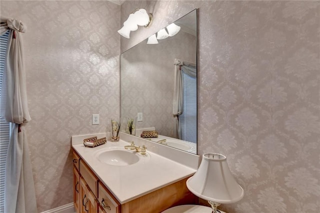 bathroom with vanity, baseboards, and wallpapered walls