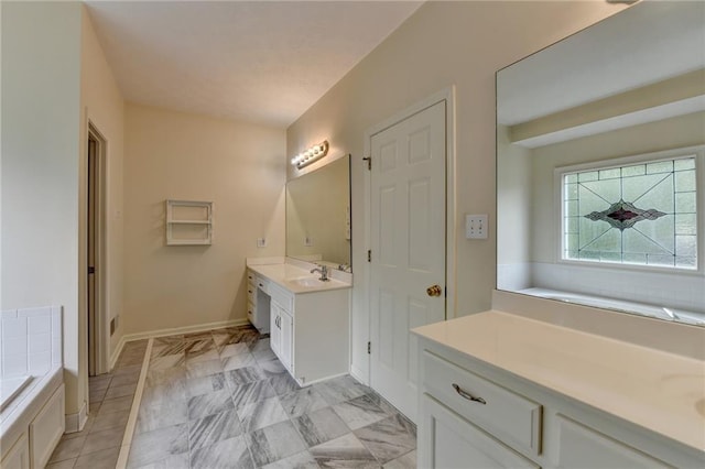 full bathroom with baseboards, a garden tub, and vanity
