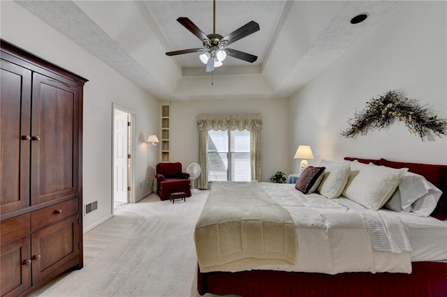 bedroom featuring ceiling fan, light carpet, a raised ceiling, baseboards, and visible vents