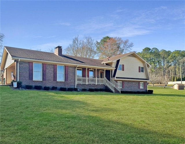 view of front of house featuring covered porch, brick siding, a chimney, and a front lawn