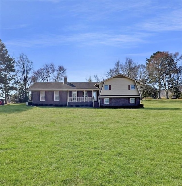 view of front of home with brick siding, a front lawn, and a gambrel roof