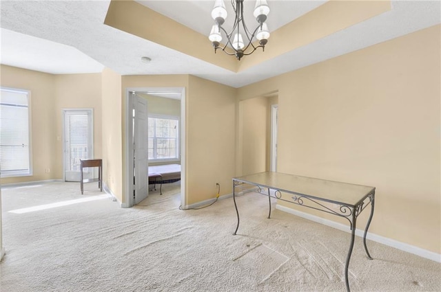 interior space with light colored carpet, an inviting chandelier, and a tray ceiling