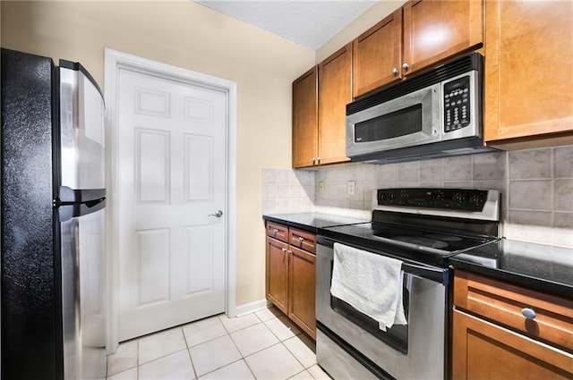 kitchen featuring light tile patterned floors, backsplash, a textured ceiling, and appliances with stainless steel finishes