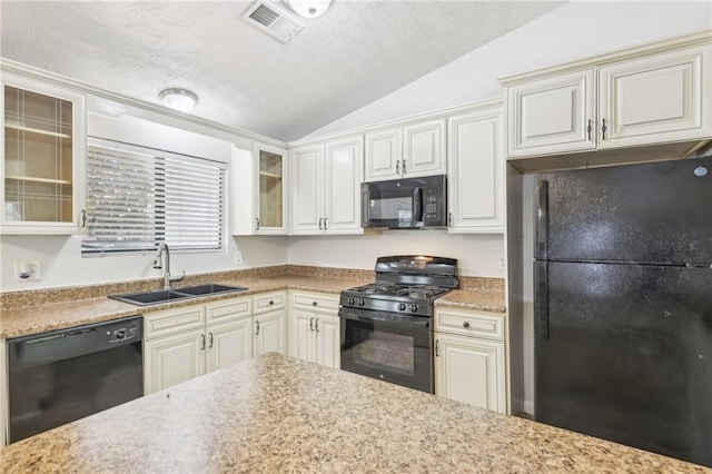 kitchen featuring black appliances, sink, a textured ceiling, lofted ceiling, and white cabinets