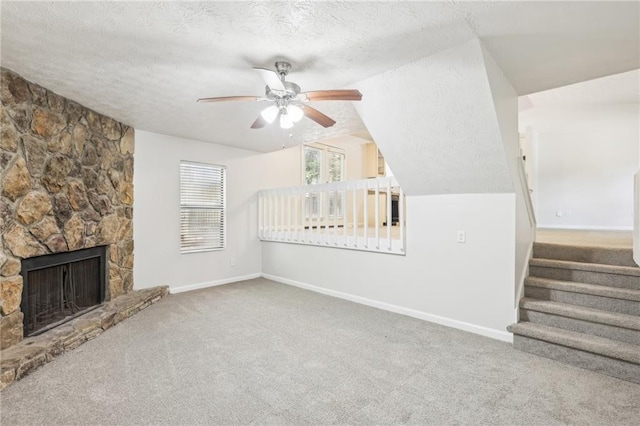 unfurnished living room with lofted ceiling, carpet, ceiling fan, a textured ceiling, and a stone fireplace