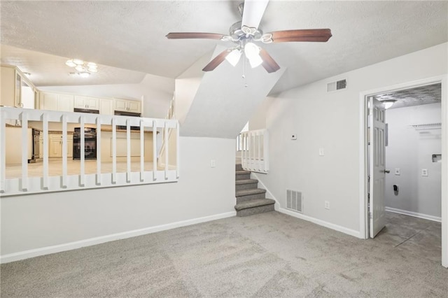 unfurnished living room featuring ceiling fan, a textured ceiling, lofted ceiling, and light colored carpet