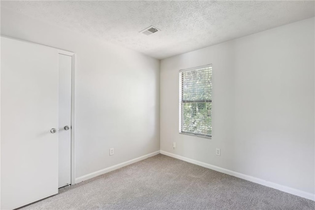 unfurnished room featuring light carpet and a textured ceiling