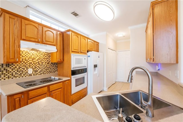 kitchen featuring a sink, visible vents, white appliances, crown molding, and under cabinet range hood