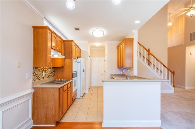 kitchen with visible vents, decorative backsplash, white appliances, light countertops, and under cabinet range hood