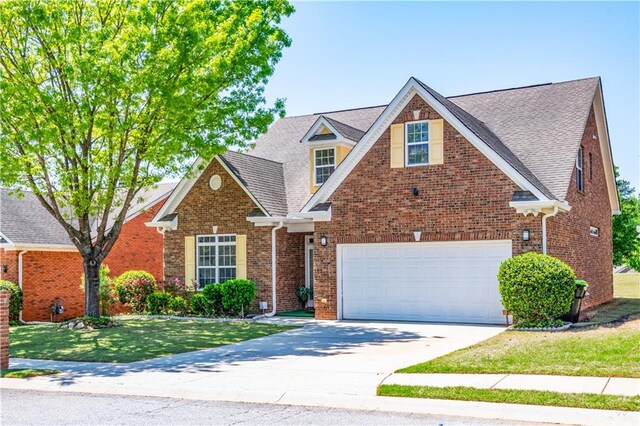 traditional-style home featuring brick siding, an attached garage, a front lawn, and concrete driveway