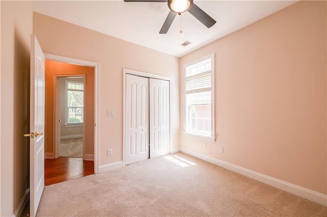 unfurnished bedroom with baseboards, carpet flooring, multiple windows, and visible vents