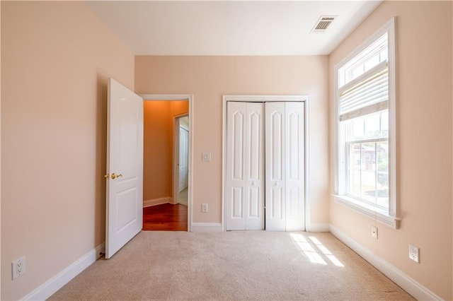 unfurnished bedroom featuring visible vents, baseboards, carpet flooring, and a closet