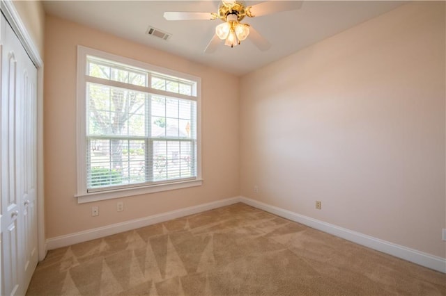 spare room with light carpet, baseboards, visible vents, and a healthy amount of sunlight