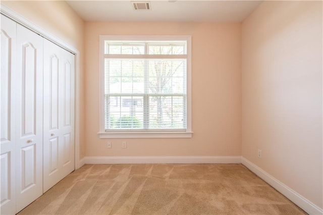 unfurnished bedroom with light colored carpet, baseboards, visible vents, and a closet