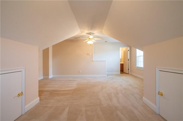 bonus room with vaulted ceiling, a ceiling fan, baseboards, and light carpet
