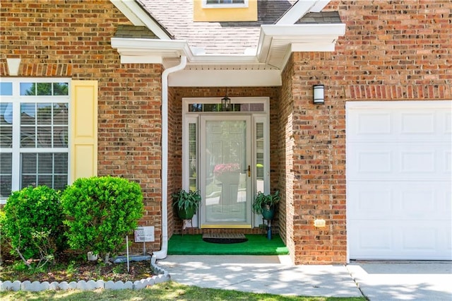 view of exterior entry with brick siding and a garage
