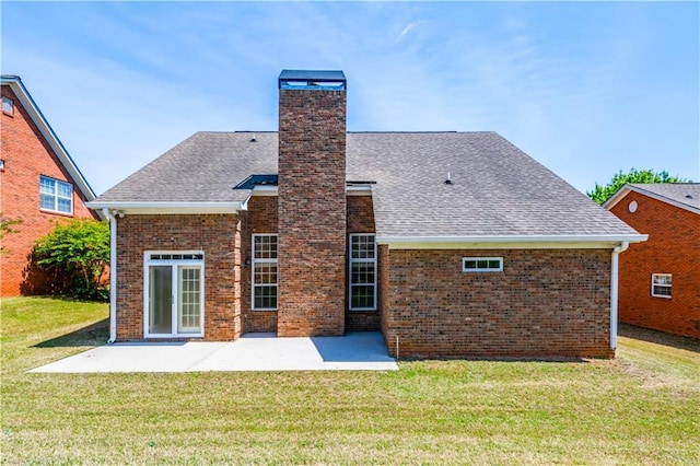 back of house featuring a patio area, a lawn, a chimney, and brick siding