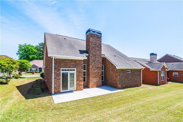 back of property featuring brick siding, a yard, a chimney, and a patio