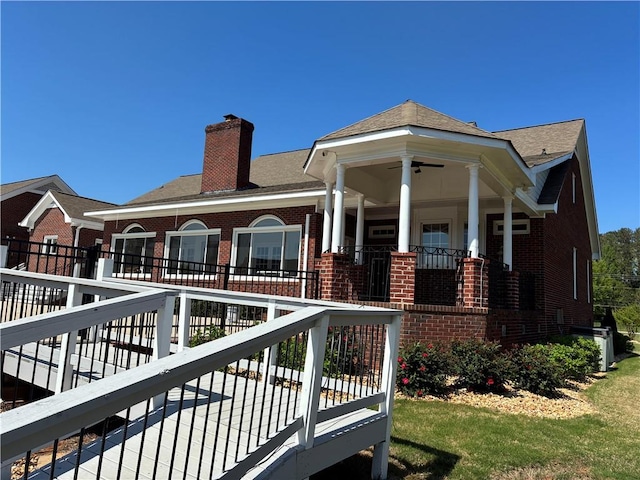 back of house featuring a chimney, brick siding, a porch, and a ceiling fan