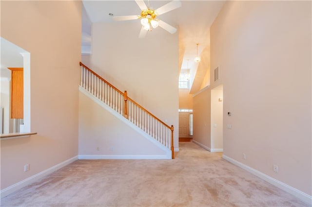 unfurnished living room featuring high vaulted ceiling, a ceiling fan, stairs, carpet floors, and visible vents