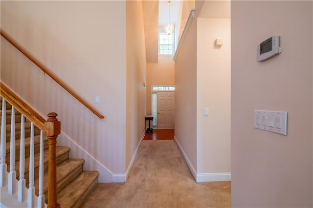 stairs with a high ceiling, carpet flooring, and baseboards
