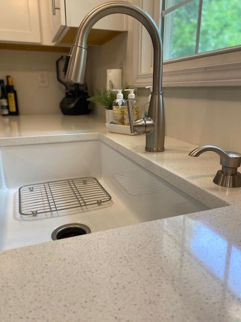 interior details featuring white cabinetry, light stone countertops, and sink