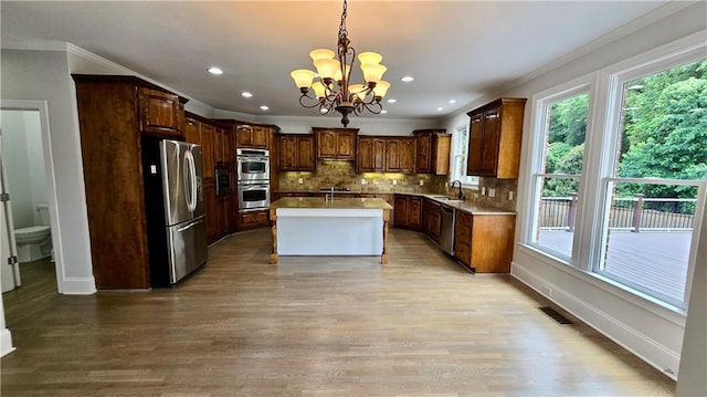 kitchen featuring a sink, backsplash, appliances with stainless steel finishes, crown molding, and a chandelier