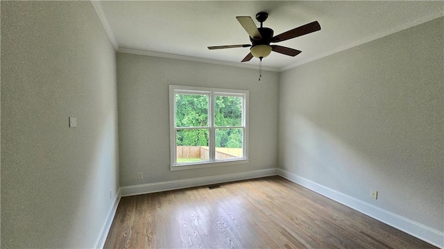 empty room with wood finished floors, baseboards, and ornamental molding