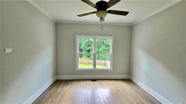 spare room with crown molding, wood finished floors, and baseboards