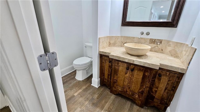 bathroom featuring toilet, vanity, baseboards, and wood finished floors