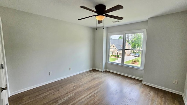 spare room with dark wood finished floors, visible vents, ceiling fan, and baseboards