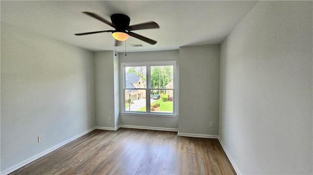 empty room with visible vents, a ceiling fan, baseboards, and wood finished floors