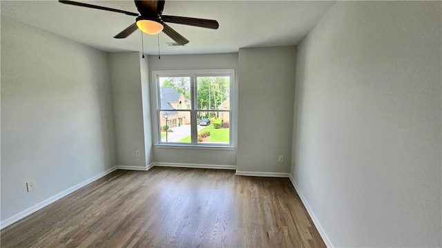 spare room with dark wood finished floors, ceiling fan, and baseboards