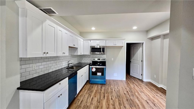 kitchen featuring visible vents, a sink, dark countertops, white cabinetry, and stainless steel appliances