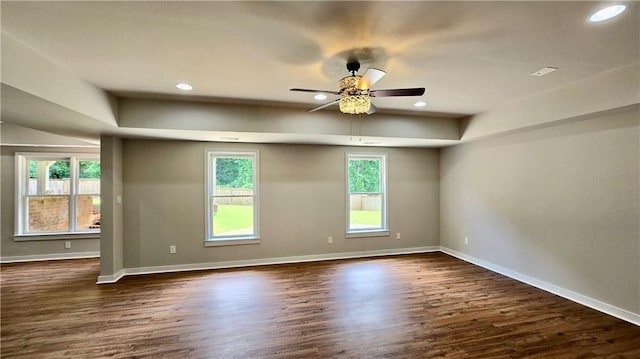 empty room with dark wood finished floors, plenty of natural light, and baseboards