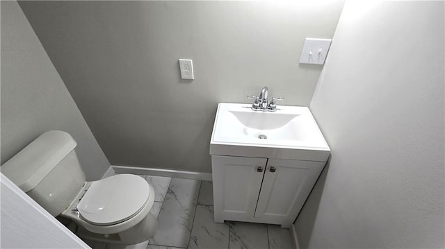 half bath with baseboards, toilet, marble finish floor, and vanity