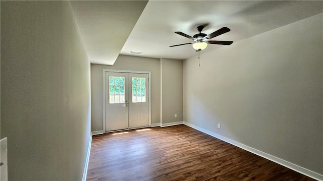 empty room with dark wood finished floors, a ceiling fan, and baseboards