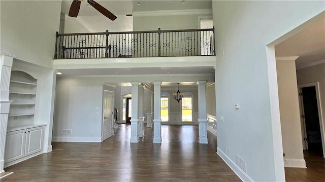 unfurnished living room with crown molding, a high ceiling, decorative columns, and ceiling fan with notable chandelier