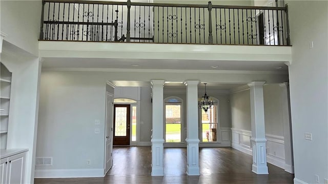 interior space featuring crown molding, a high ceiling, wood finished floors, and visible vents