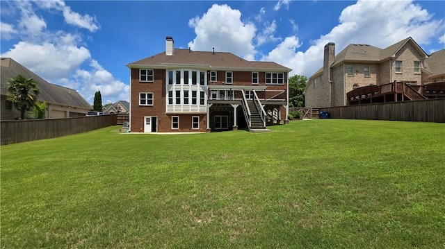 rear view of house with a lawn, a chimney, a fenced backyard, and stairs