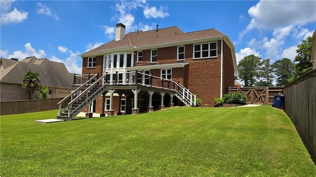 rear view of house featuring a fenced backyard, stairs, a yard, brick siding, and a chimney