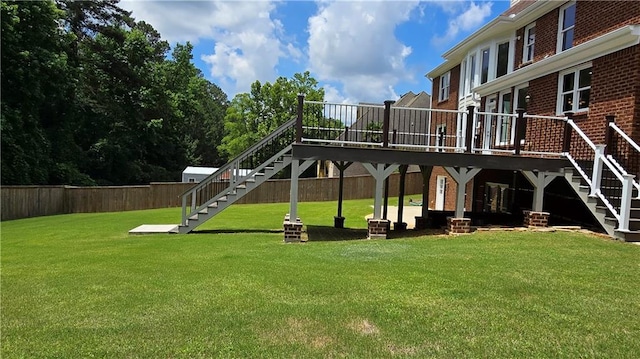 view of play area featuring stairway, a lawn, a deck, and fence