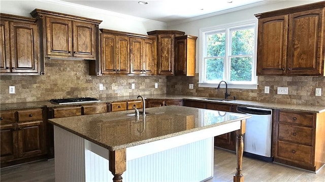 kitchen featuring ornamental molding, black gas stovetop, a sink, dark stone countertops, and stainless steel dishwasher