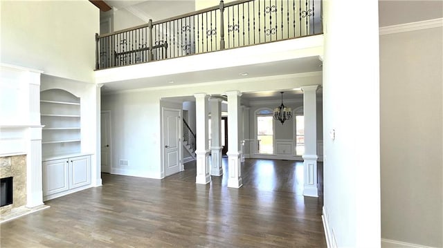 unfurnished living room featuring crown molding, built in features, stairs, a premium fireplace, and wood finished floors