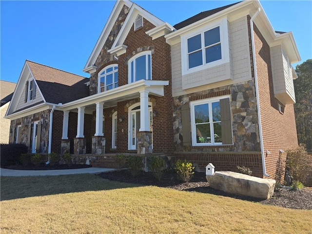 view of front of home with brick siding, stone siding, a porch, and a front yard