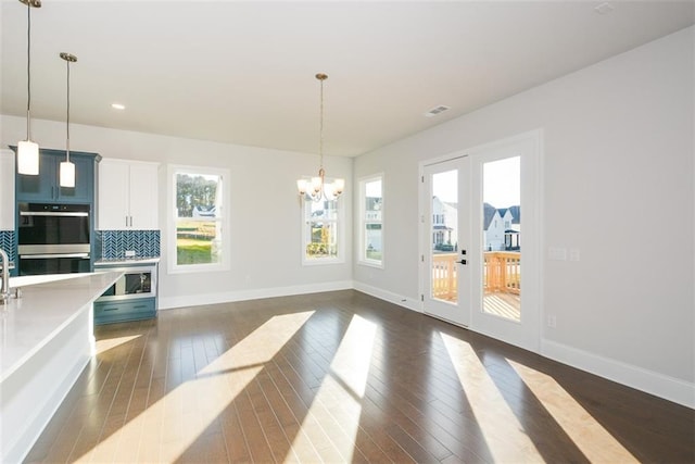 dining area with french doors, dark hardwood / wood-style floors, and an inviting chandelier