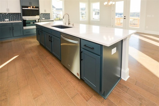 kitchen with a wealth of natural light, sink, tasteful backsplash, stainless steel dishwasher, and a kitchen island with sink