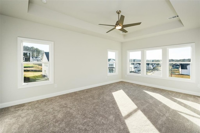 spare room with a tray ceiling, ceiling fan, and carpet flooring